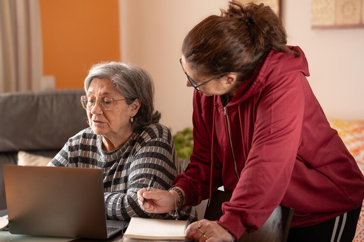 Foto mujer tomando notas mientras su madre está en la computadora