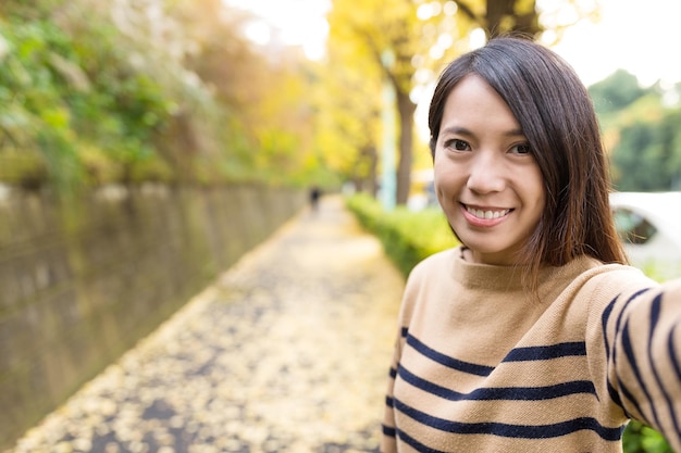 Mujer tomando selfie en el camino del ginkgo