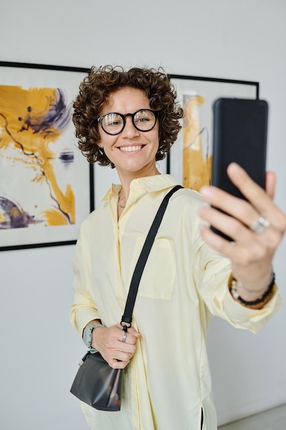 Mujer tomando selfie en galería de arte