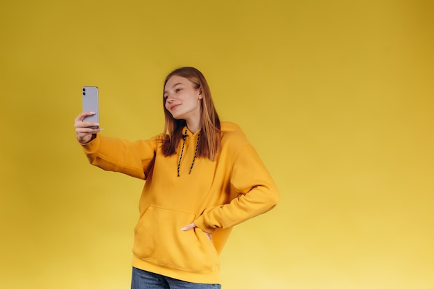 Mujer tomando selfie sobre fondo amarillo El adolescente está vestido con un flaco amarillo La niña es feliz