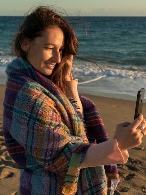 Foto mujer tomando una selfie con su teléfono móvil en la playa