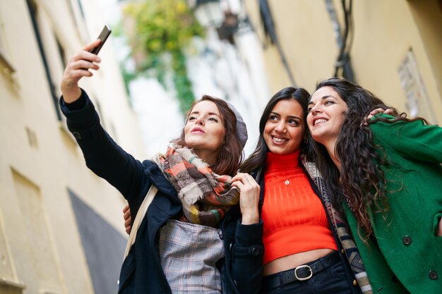 Foto mujer tomando una selfie con sus amigos por teléfono móvil