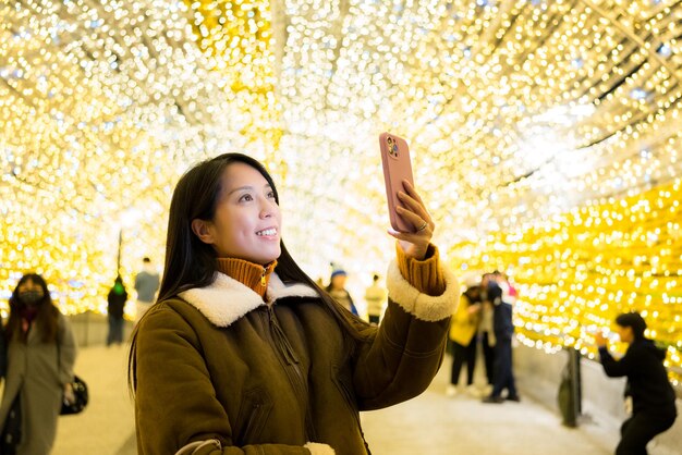 Mujer tomando selfies en el teléfono móvil en la ciudad por la noche