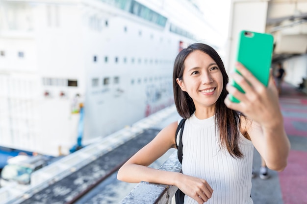 Mujer tomando selife por teléfono móvil en la terminal de cruceros