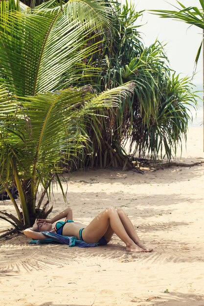 Mujer tomando el sol en la arena cerca del océano