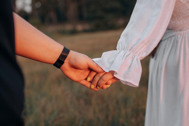 Una mujer tomándose de la mano con un vestido blanco y un vestido blanco sostiene su mano.