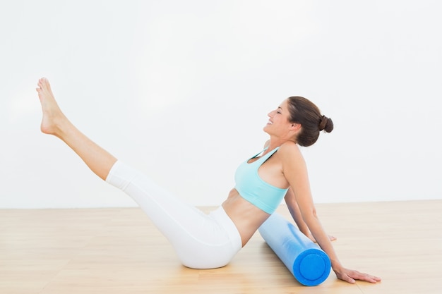 Mujer tonificada haciendo la pose del barco en el gimnasio