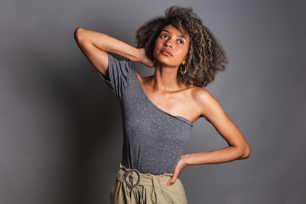 Una mujer con un top gris y pantalones cortos de color caqui posa para una foto.