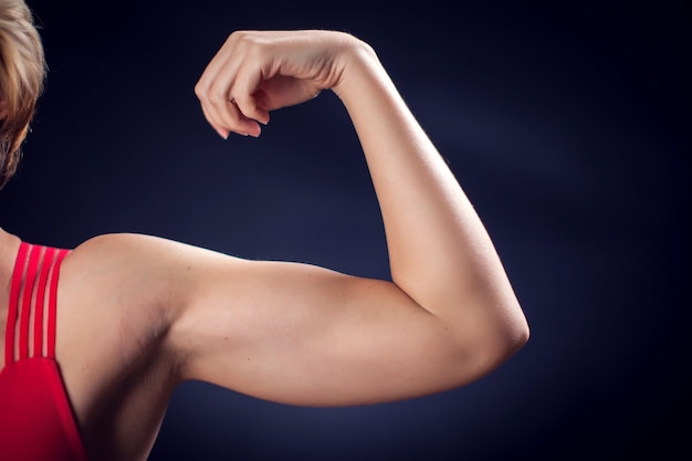 Foto mujer en top rojo mostrando tríceps y bíceps. concepto de fitness y salud