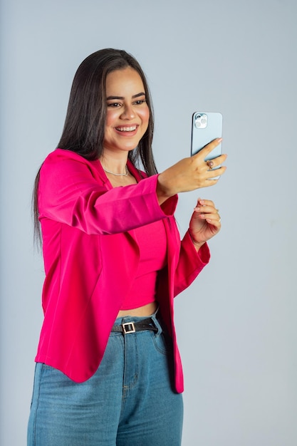 Una mujer con un top rosa se está haciendo un autorretrato con su teléfono.