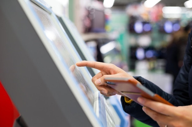 Mujer toque en la máquina expendedora de billetes con celular