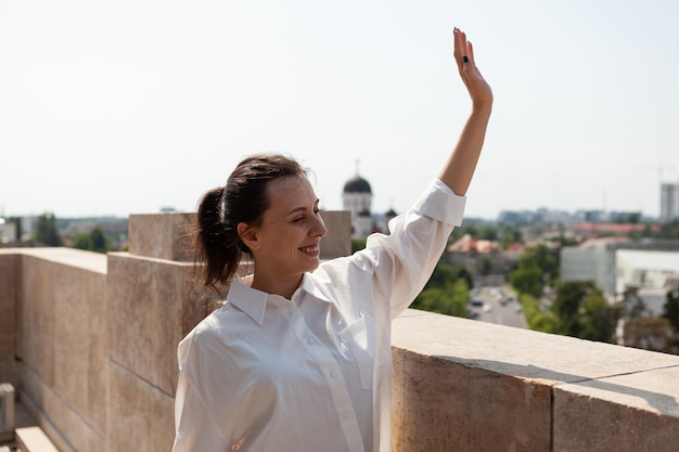 Mujer toursit saludando a la gente mientras está de pie en la terraza de la torre