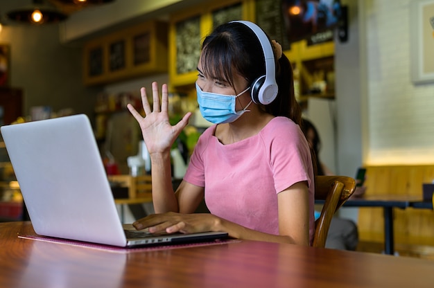 Foto la mujer trabaja desde casa con máscara protectora y espera a que la situación epidémica mejore pronto en casa. coronavirus, covid-19, trabajo desde casa (fmh),