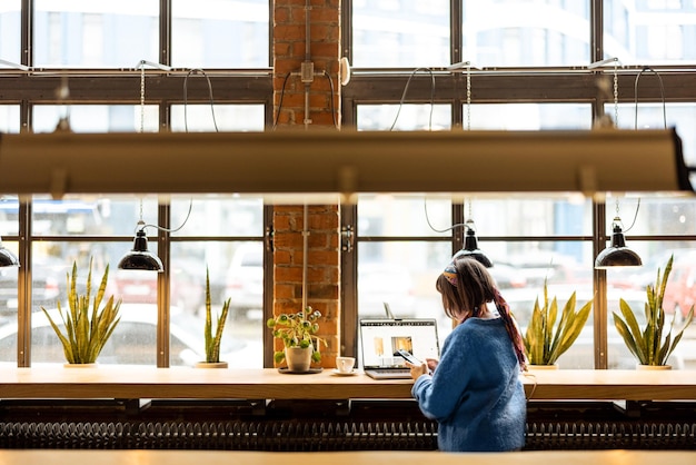 La mujer trabaja en la computadora portátil en la cafetería