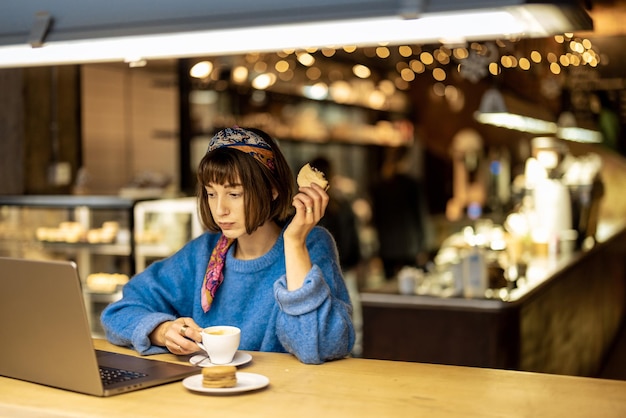 La mujer trabaja en la computadora portátil en la cafetería