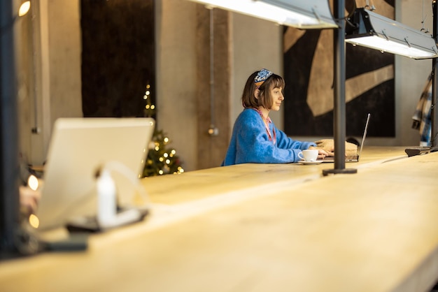 La mujer trabaja en la computadora portátil en la cafetería