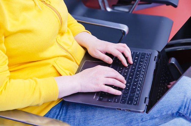 Mujer trabaja en una computadora portátil colocándola en su regazo Mujer turista sentada mientras espera un vuelo Programación de tecnología empresarial y concepto de educación Primer plano de una mujer escribiendo en una computadora portátil