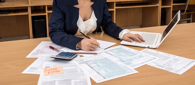 Mujer trabaja en la computadora portátil y llenando el formulario de impuestos