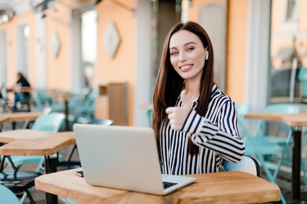 La mujer trabaja en la computadora portátil sentado en la cafetería