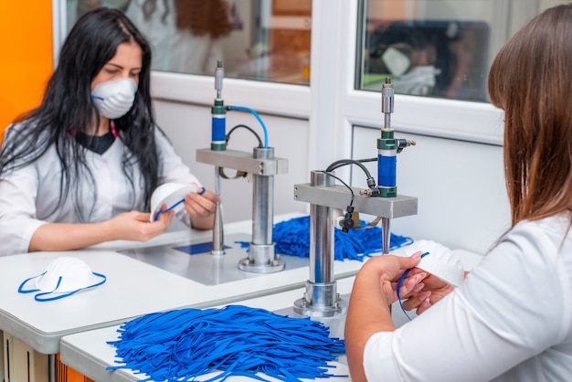 Una mujer trabaja en una máquina para la fabricación de máscaras médicas con nanofibras y bucles de soldadura con ultrasonido.