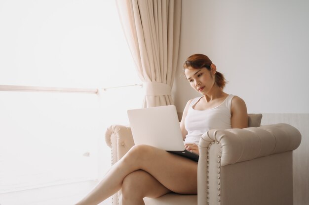 La mujer trabaja y se relaja con la computadora portátil en el sofá concepto de trabajo del hotel