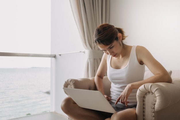 La mujer trabaja y se relaja con la computadora portátil en el sofá concepto de trabajo del hotel