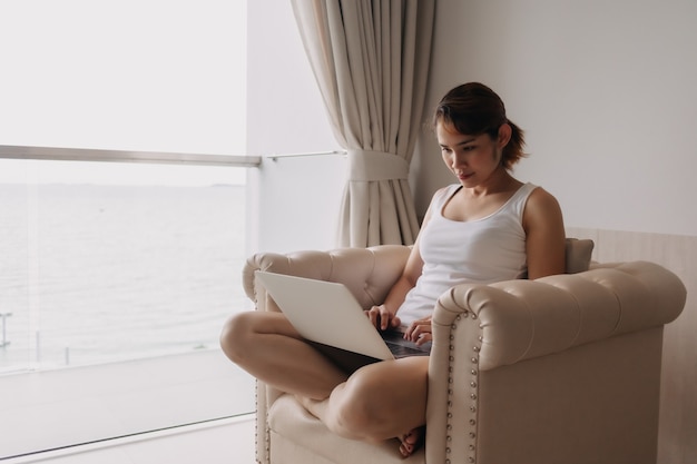 La mujer trabaja y se relaja con la computadora portátil en el sofá concepto de trabajo del hotel