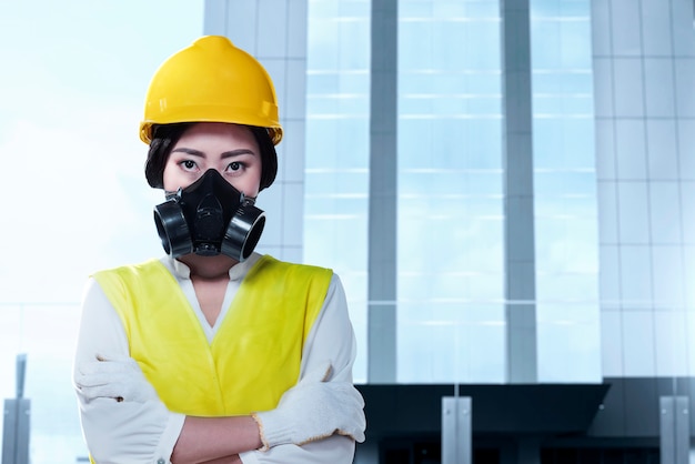 Mujer trabajadora asiática con una máscara protectora y casco amarillo de pie