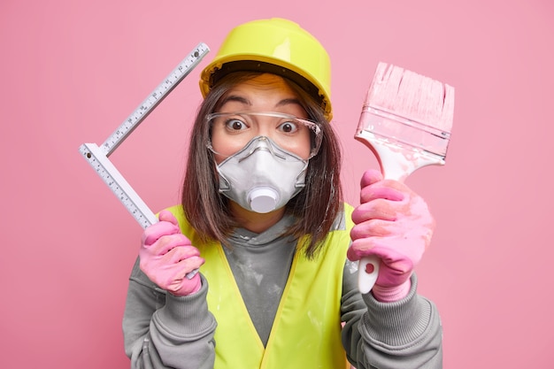 Mujer trabajadora asiática con pincel y uniforme. Trabajador de construcción industrial o renovación de viviendas