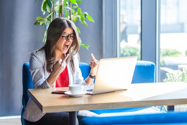 Mujer trabajadora emocional sentada en la oficina con su computadora portátil