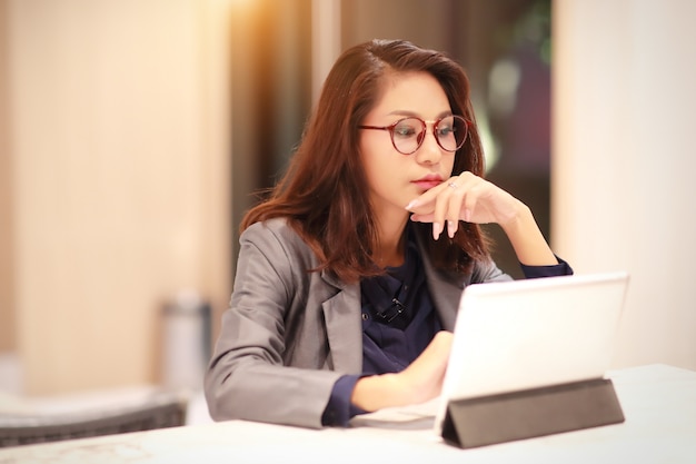 Foto mujer trabajadora y encantadora con gafas usando tableta (concepto de trabajo desde casa)