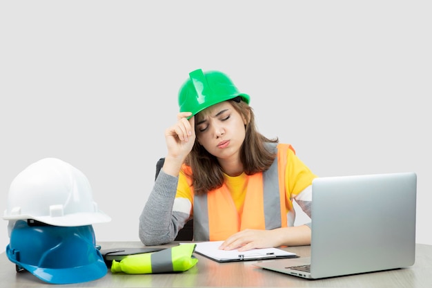 Mujer trabajadora en uniforme sentada en el escritorio con computadora portátil y portapapeles. foto de alta calidad