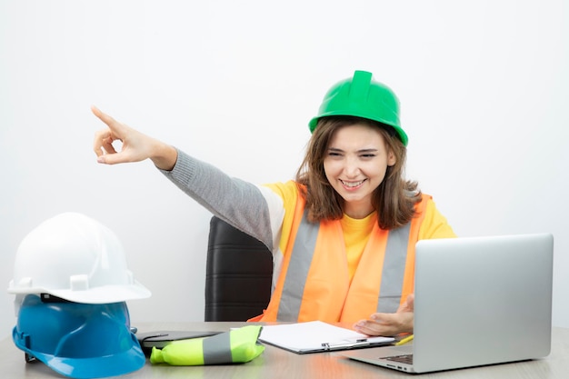 Mujer trabajadora en uniforme sentada en el escritorio con computadora portátil y portapapeles. foto de alta calidad