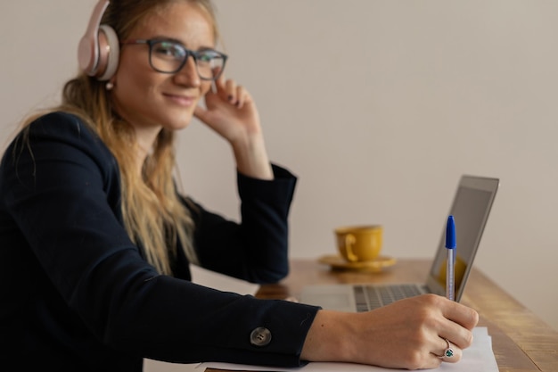 Foto mujer trabajando en casa con computadora portátil y papeles en el escritorio y auriculares casa oficina cuaderno gris