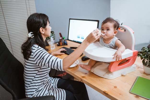 Mujer trabajando en casa y cuidando a su bebé