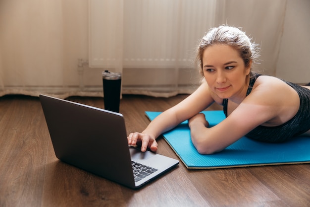 Foto mujer trabajando en casa sobre una estera de yoga