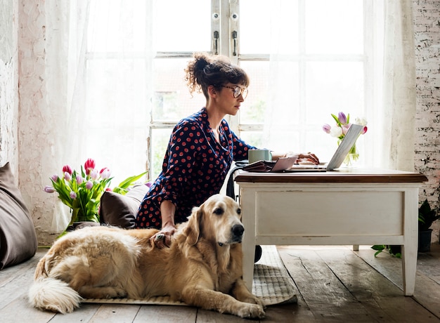 Mujer trabajando en casa con su perro.