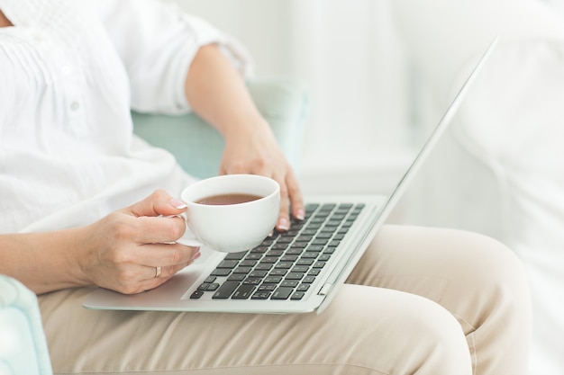 Mujer trabajando en una computadora portátil y tomando café