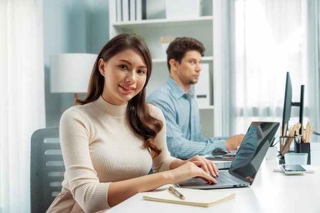 Mujer trabajando en una computadora portátil tomando nota para posar para mirar la cámara Postulado