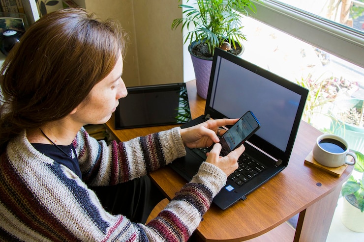 Foto mujer trabajando con un cuaderno en el lugar de trabajo tableta digital teléfono móvil café y plantas