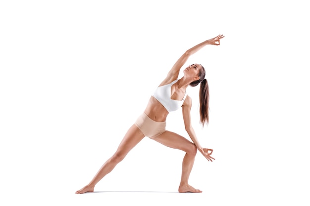 Mujer trabajando ejercicio de yoga, retrato de cuerpo entero, aislado en blanco. Equilibrio y meditación, armonía de cuerpo y mente.