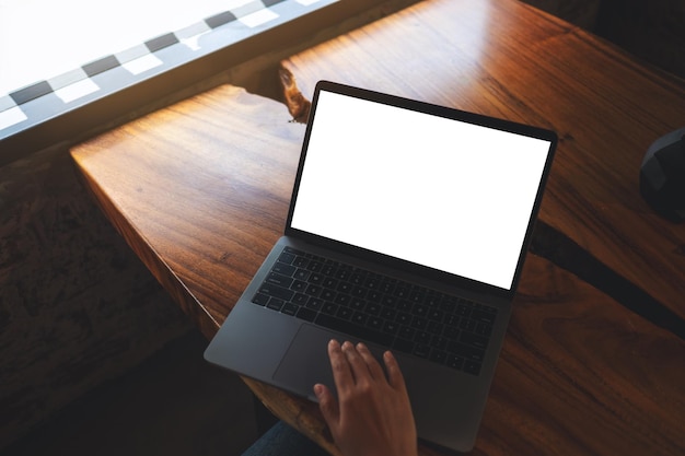 Mujer trabajando y escribiendo en una computadora portátil con una pantalla de escritorio blanca en blanco en la oficina