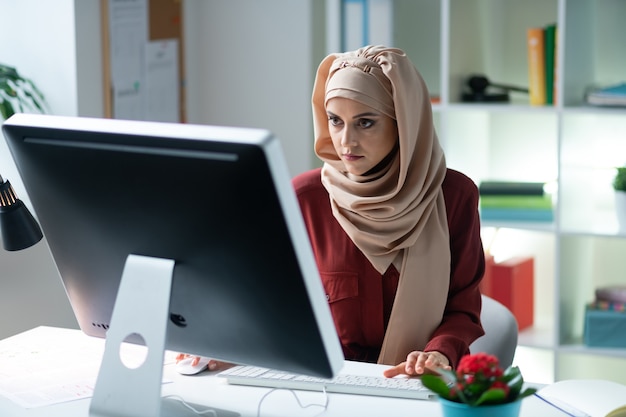 Mujer trabajando. Joven musulmana con hiyab trabajando en equipo sintiéndose sobrecargado