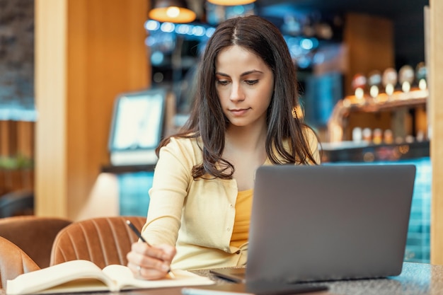 Mujer trabajando en una laptop en un café moderno