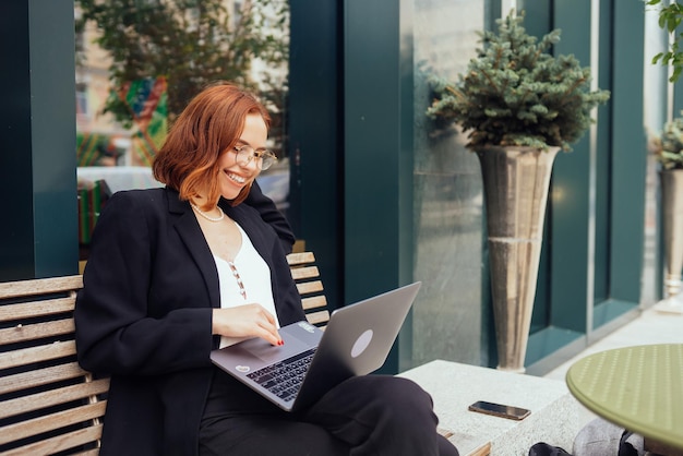 Mujer trabajando en una laptop escribiendo sentada en un café bebiendo café