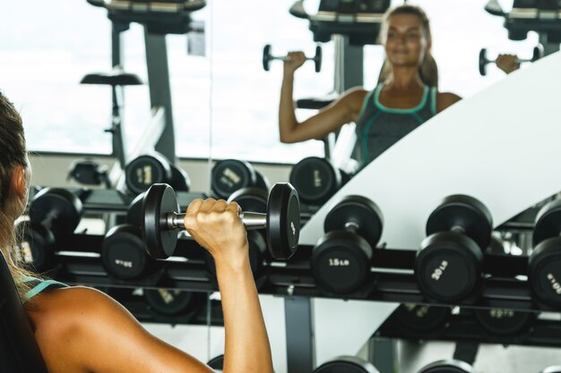 Foto mujer trabajando con pesas en el gimnasio