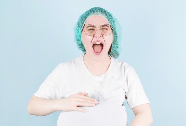 Mujer en trabajo de parto presiona para dar a luz. Embarazo y parto en pared azul.