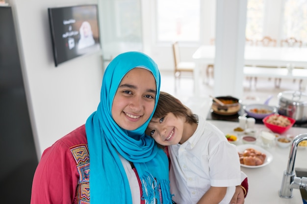 Mujer tradicional musulmana con pequeño hijo en cocina blanca moderna