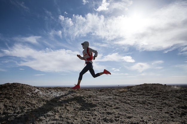 Mujer trail runner cross country corriendo sobre dunas de arena del desierto