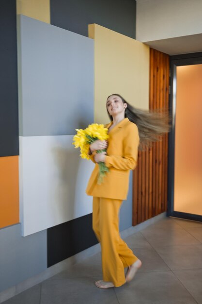 Una mujer con un traje amarillo y con flores en la mano 4629